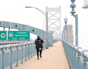 Tarir Satterfield-Rowe of Camden jogs across a smoke shrouded Ben Franklin Bridge
