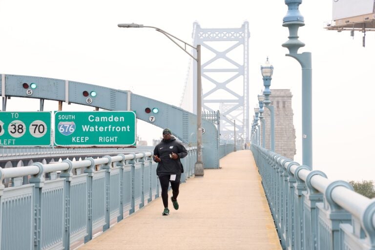 Tarir Satterfield-Rowe of Camden jogs across a smoke shrouded Ben Franklin Bridge