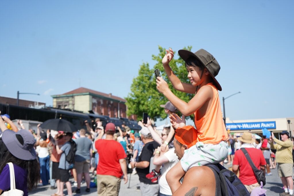 A young train fan greets the massive steam locomotive