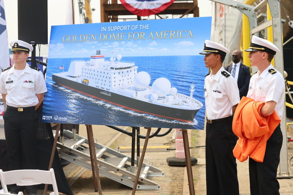 Cadets stand in front of a mockup of the Golden Defender at the Hanwha Philly Shipyard