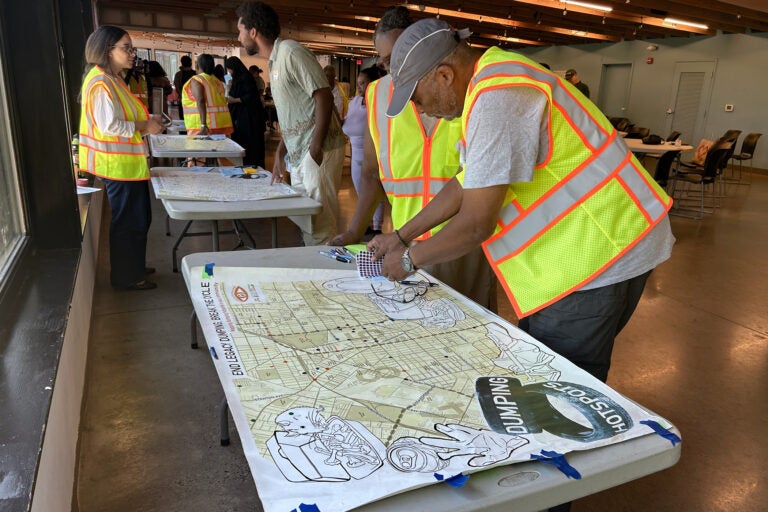 Members of Trash Academy and other attendees place stickers on maps indicating the locations of illegal dumping hotspots in their Philadelphia neighborhoods