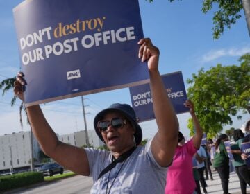 Election 2026 Postal Service Yvonne Daniels holding up a sign at a pro-USPS protest.