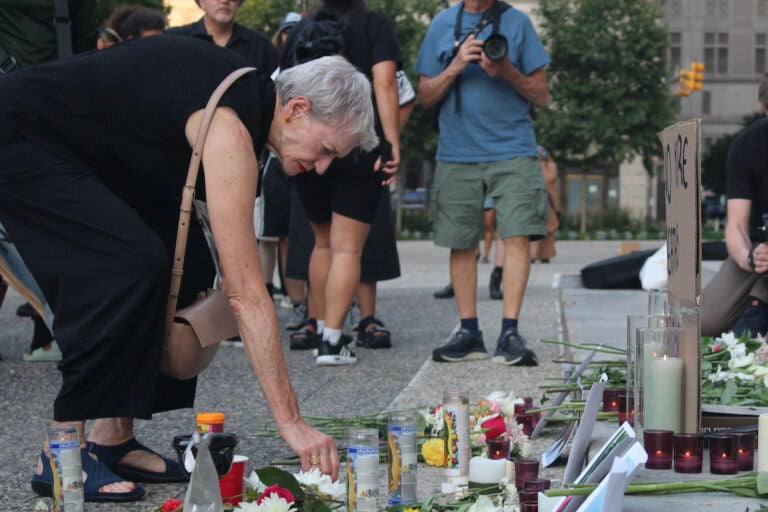 People placing items at the vigil for those killed by ICE officers.