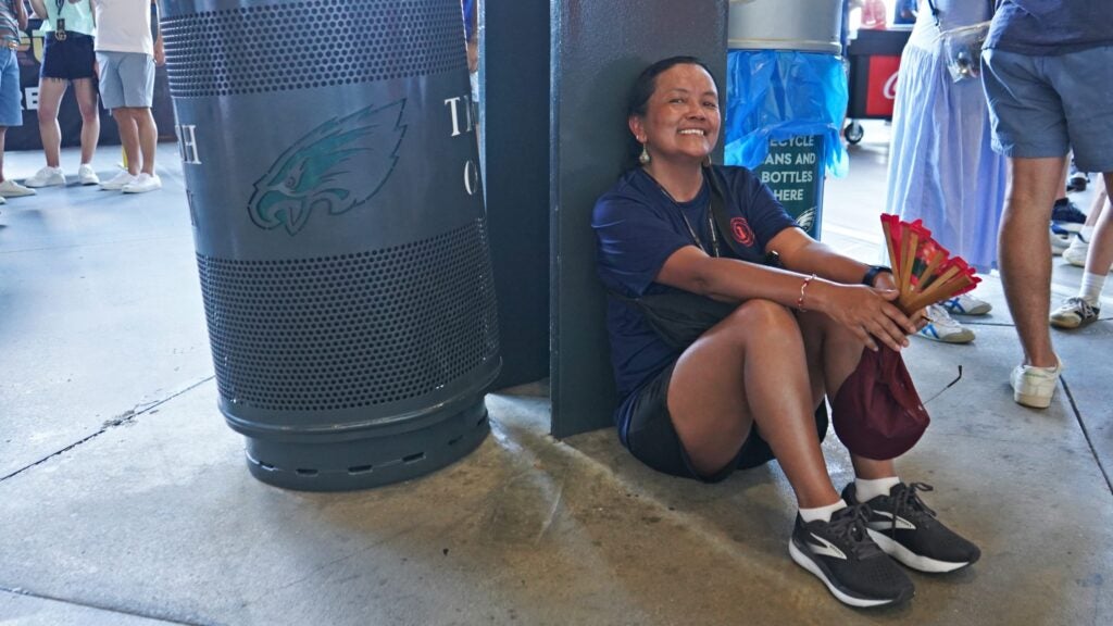 Dee Sherpa sitting on the ground resting at the stadium.