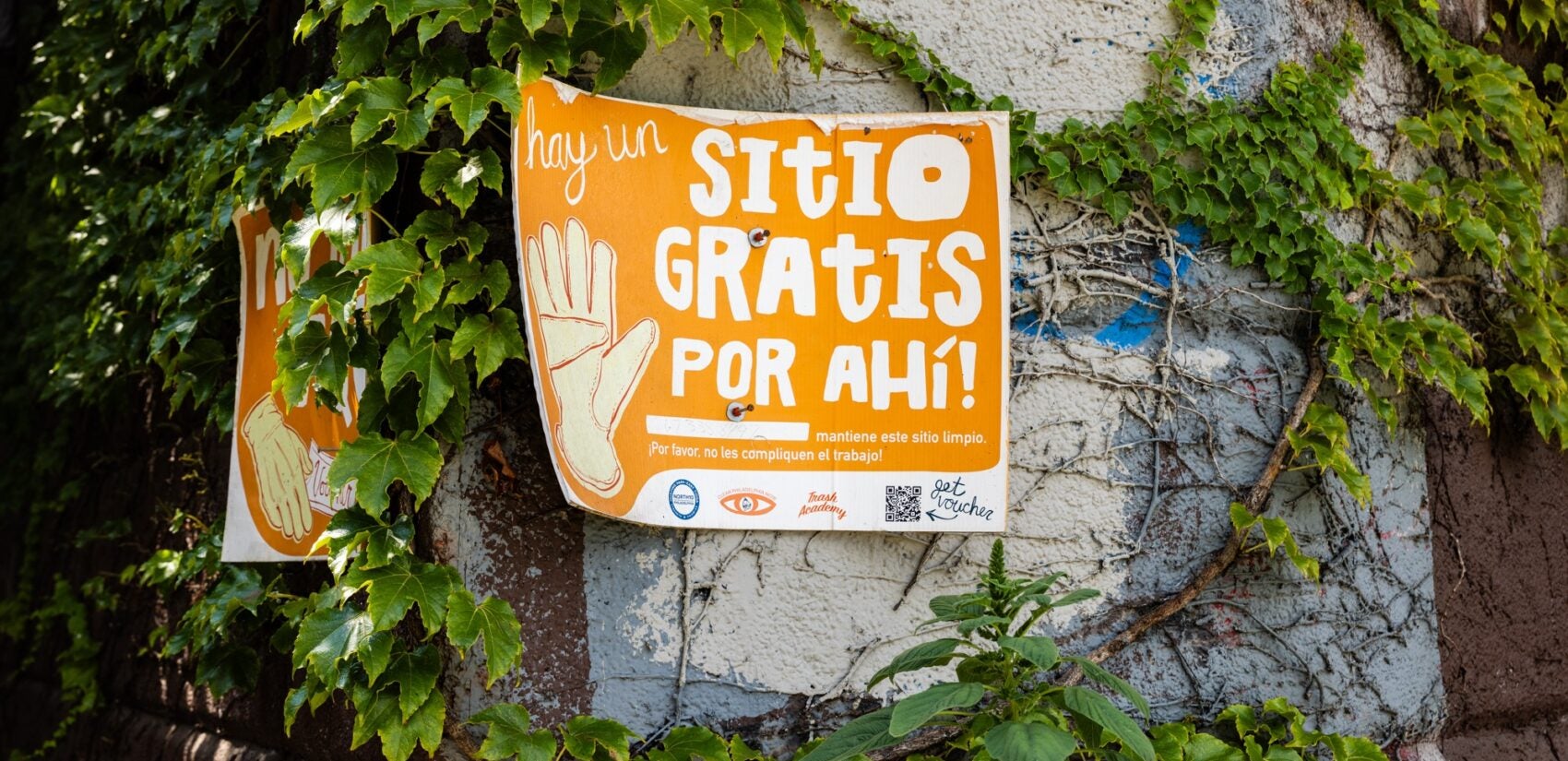 A sign posted by North10 reads hay un SITIO GRATIS POR AHÍ! mantiene este sitio limpio. ¡Por favor, no les compliquen el trabajo!