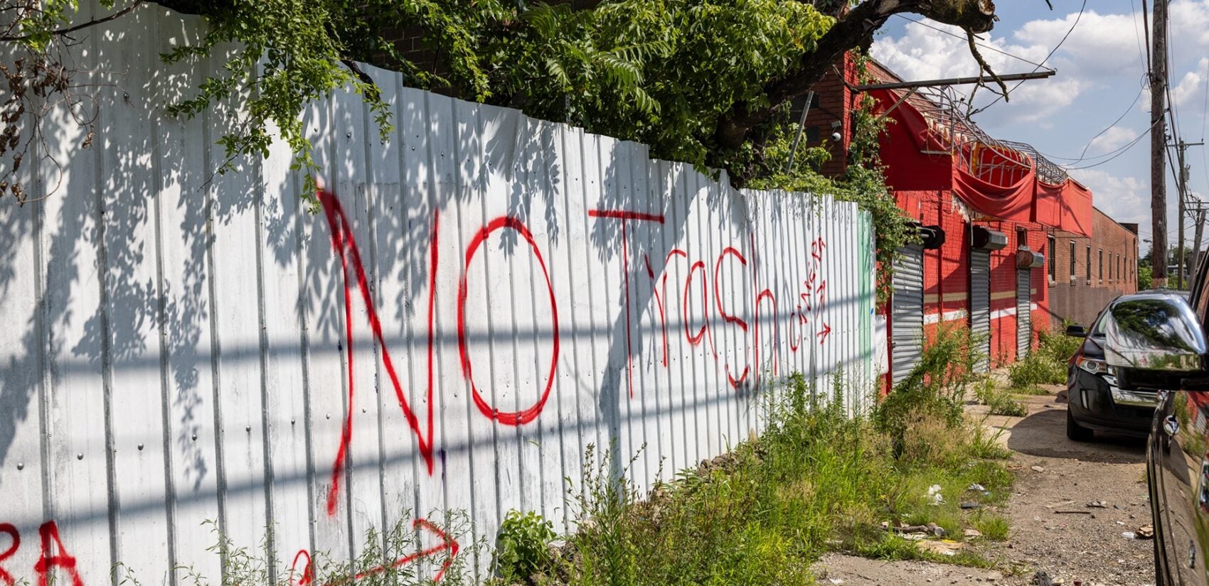 a fence is spray-painted reading NO Trash is discouraged on the fence of a business near West Pike Street and Old York Road in North Philadelphia