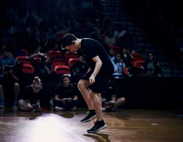 07 31 2026 k paynter jump rope champ-4 Zach Peckman is jumping rope at the competition in Buffalo, NY. He is hunched forward and is whipping the rope so quickly it is barely visible. A crowd of onlookers watch.