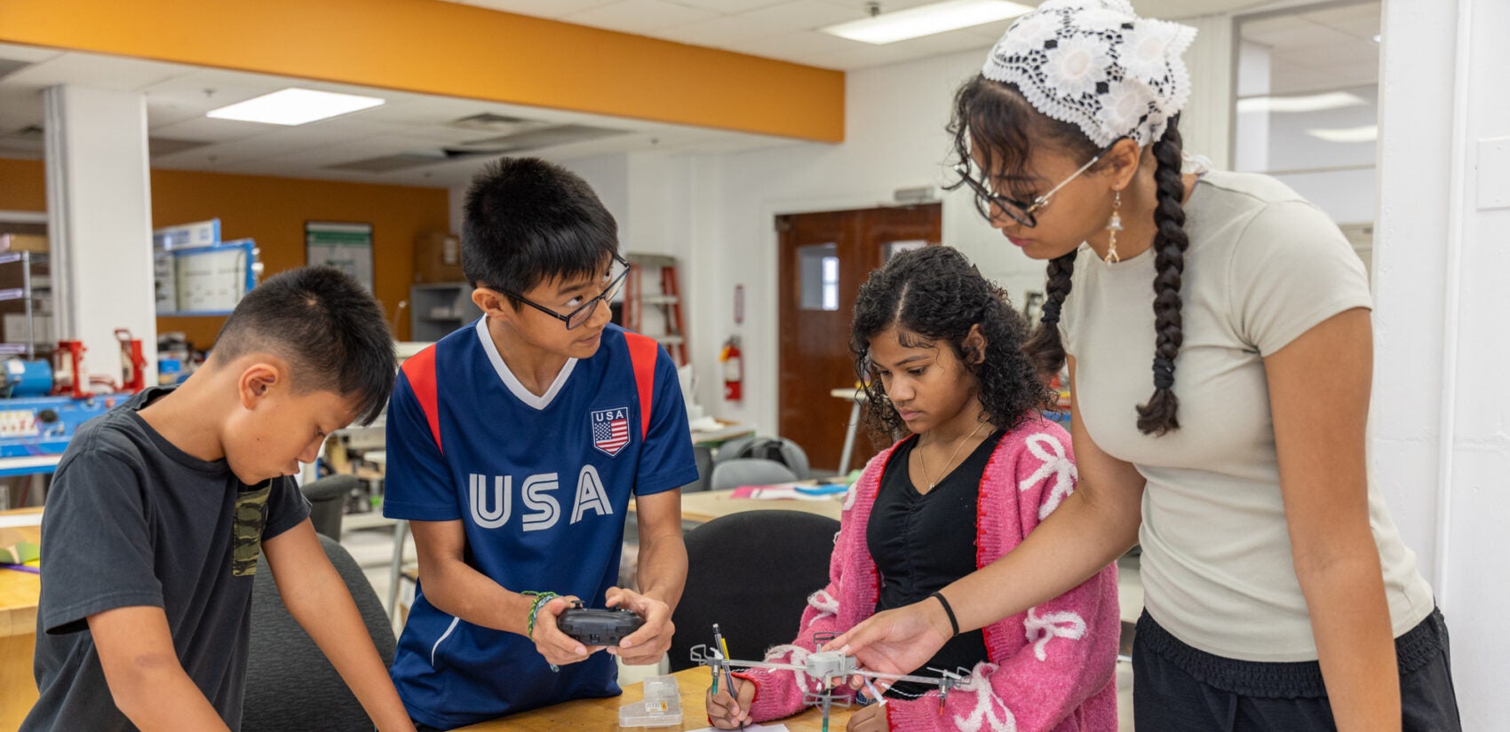 Four children at a table building a drone