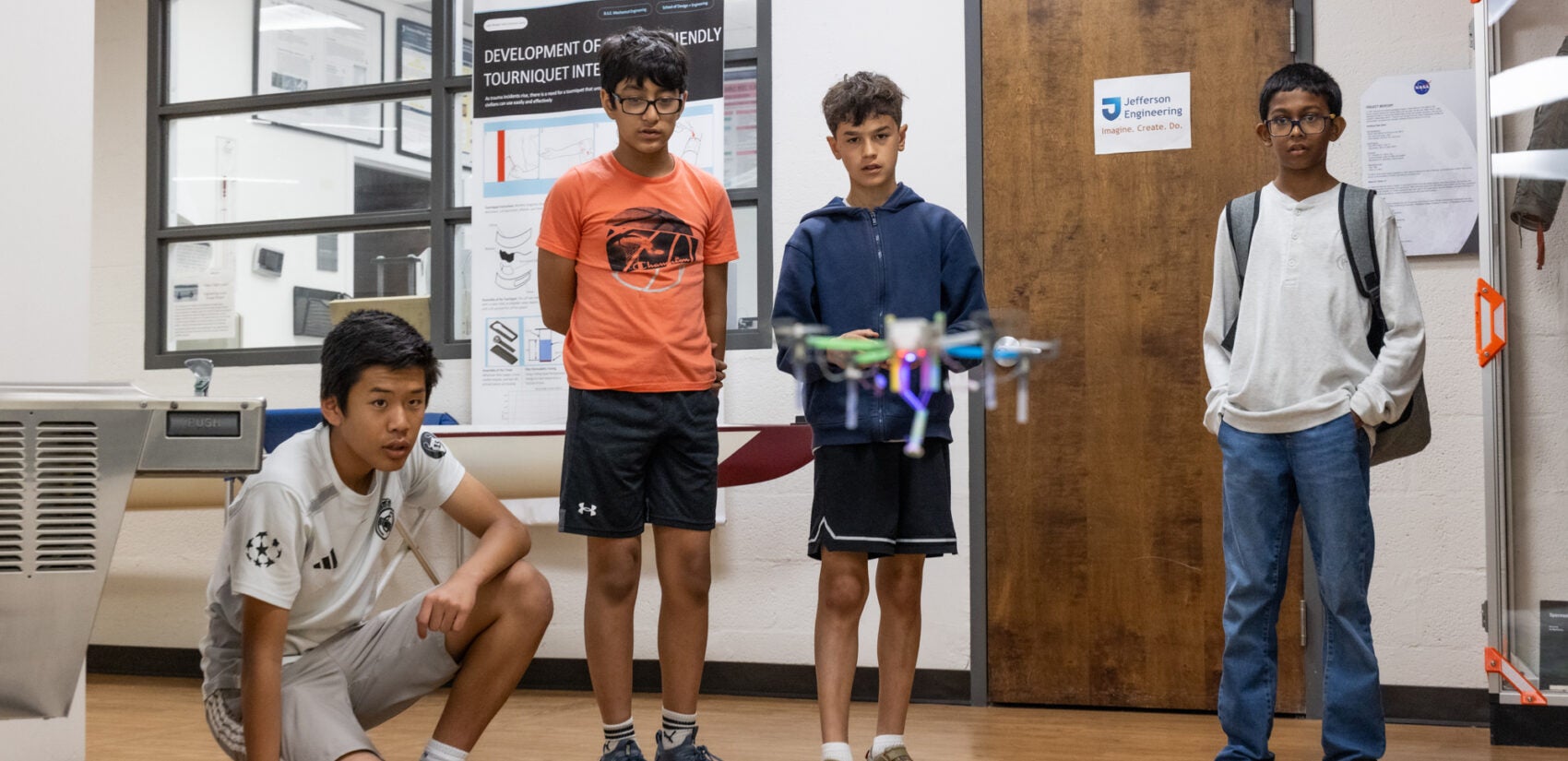 Four children watch a drone in the air