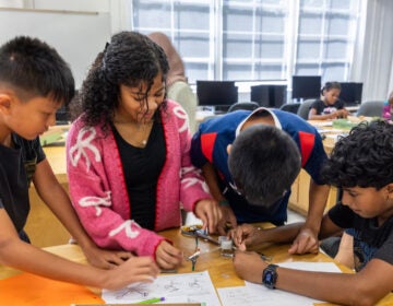 Four children at a table building a drone