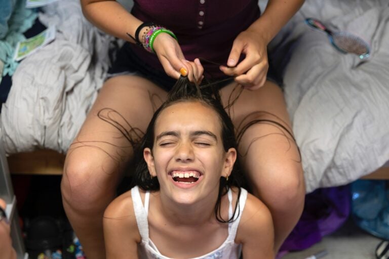 A camp counselor braids Nili Suissa’s hair