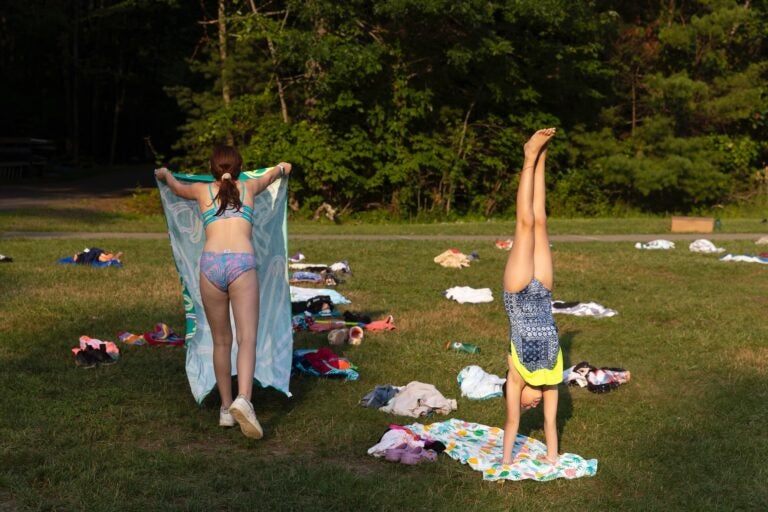 Morgan Bloomfield shakes out her towel while Eliza Goodman does a handstand