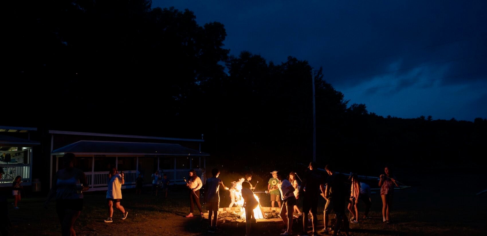 Campers roast marshmallows at an evening bonfire