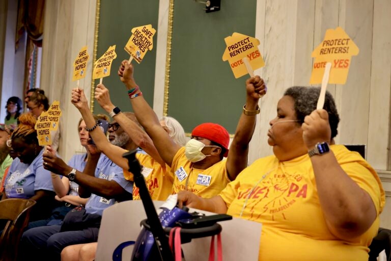 Members of Renters United One PA attend a Philadelphia City Council meeting and hold signs reading messages like PROTECT RENTERS! VOTE YES