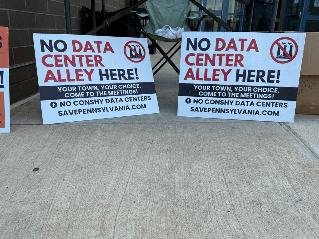 Two signs read "no data center alley here" outside a Plymouth Township Zoning Heard Board meeting