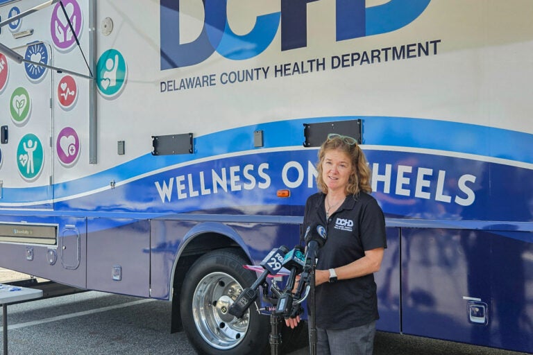 Lora Werner speaking in front of the Wellness on Wheels mobile health clinic
