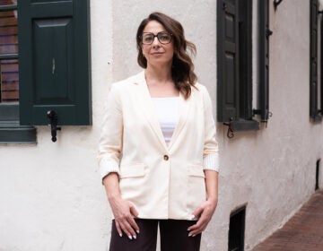 Emily Mello, the new executive director for Mural Arts Philadelphia, wears a white suit and black pants in front of a building