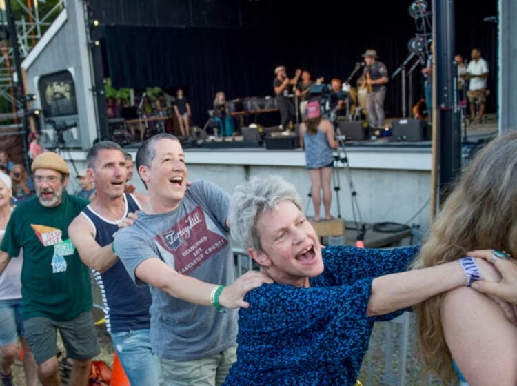 Audience members form a conga line while a band performs onstage