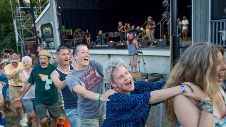 Audience members form a conga line while a band performs onstage