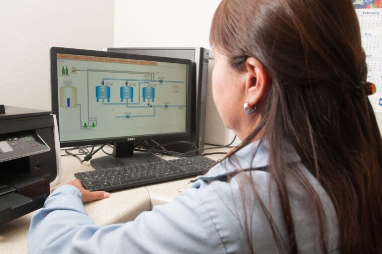 a worker looks at a computer to a water treatment facility