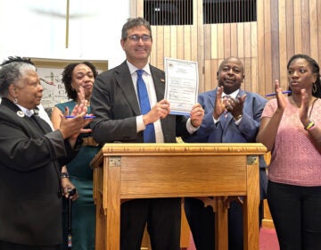 Delaware Governor Matt Meyer and lawmakers celebrate the signing of a state Voting Rights Act, with Meyer holding the bill up
