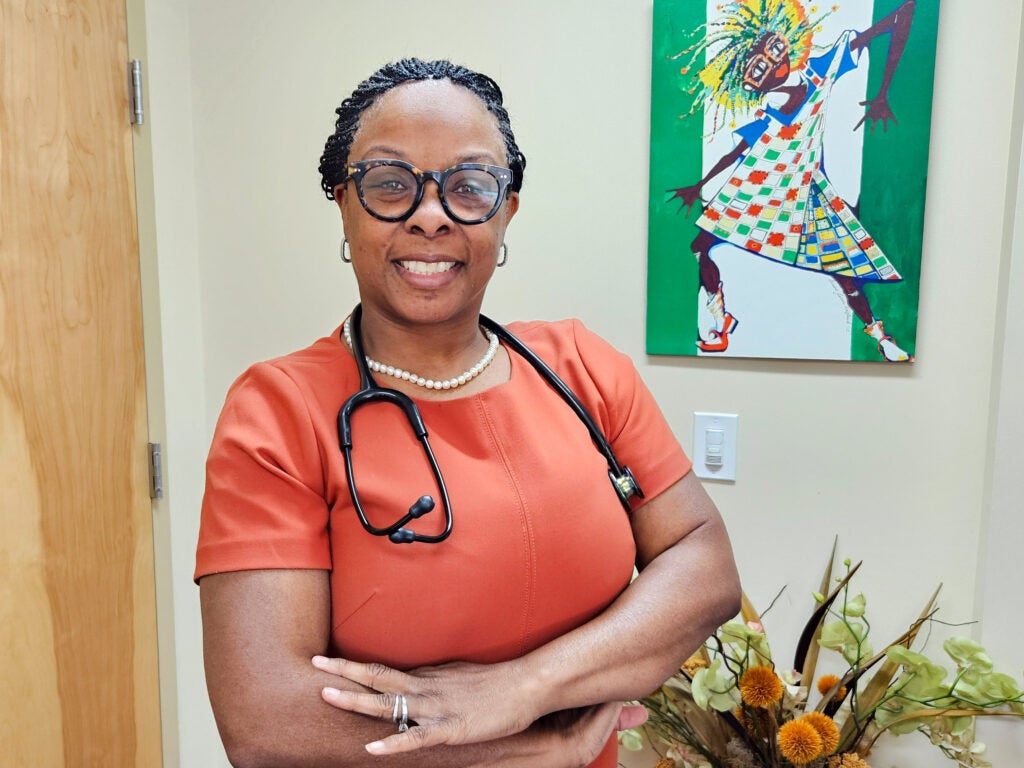 A woman doctor in red scrubs with a stethoscope around her neck