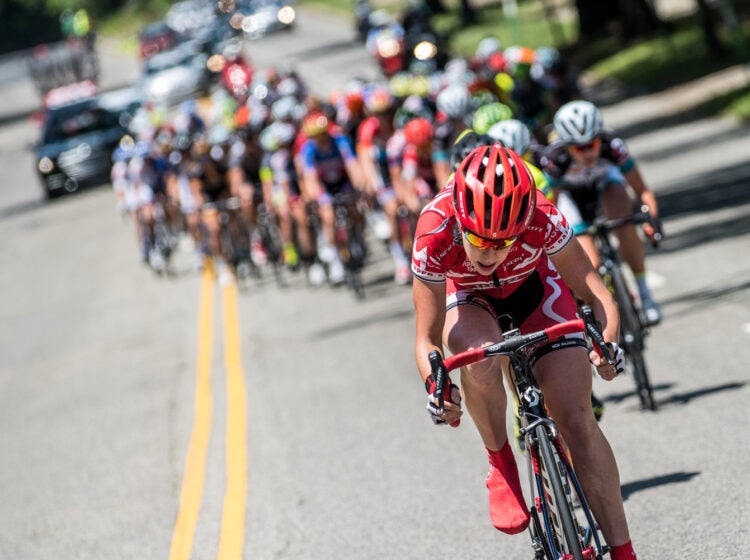 Philly2015DParks Women Kelly Drive-0954 a competitor rides her bicycle in front of other cycling competitors along a road