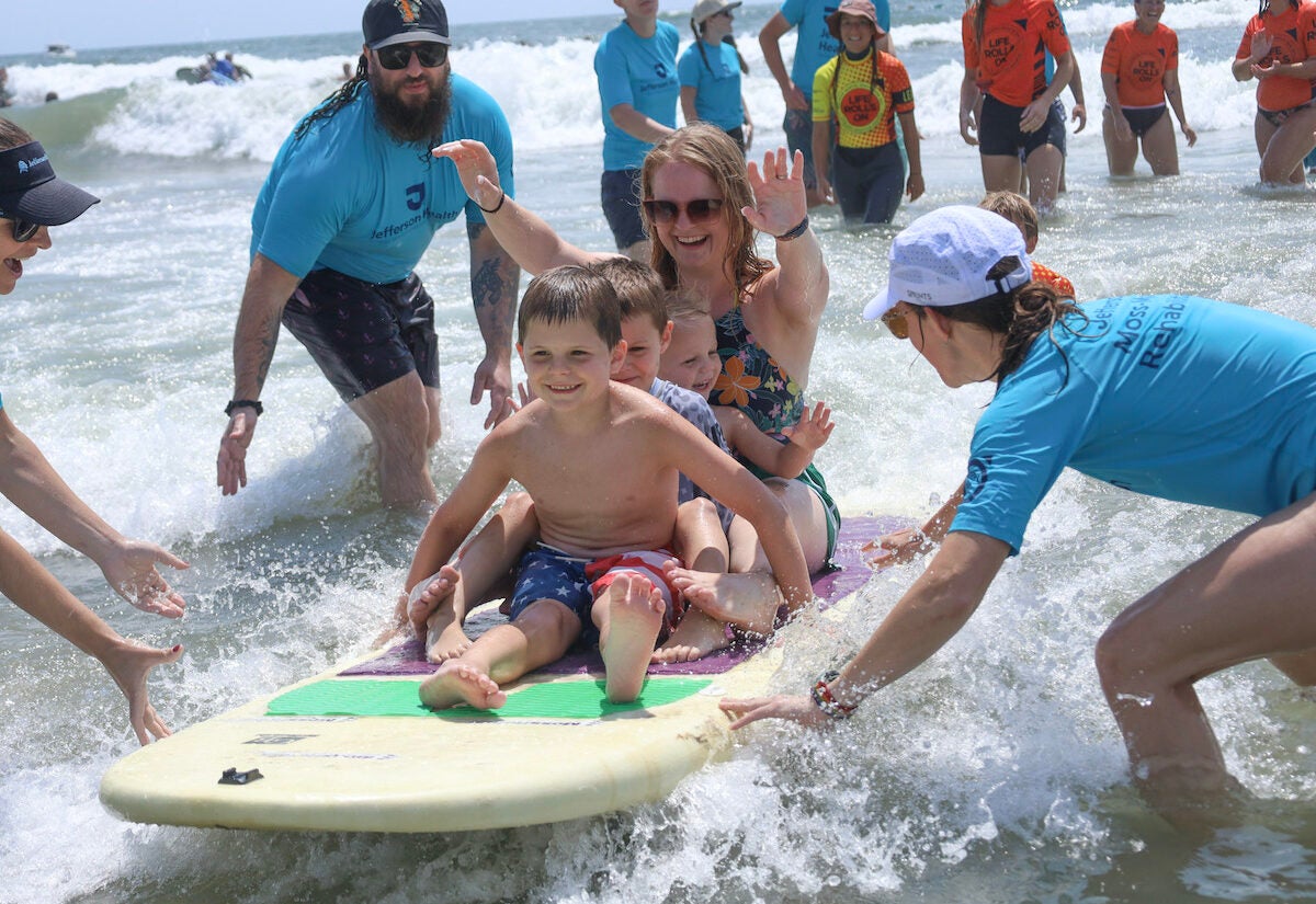 Kim Houck suurfs with sons Robin, Dylan and Peter
