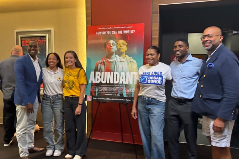 People standing next to a poster for the documentary Abundant