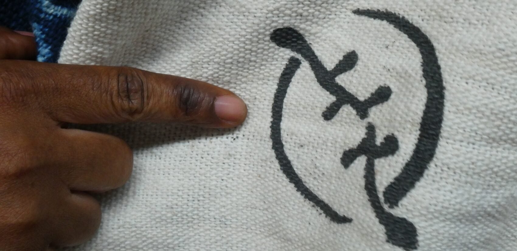 Rose Dousuah points to a symbol on fabric