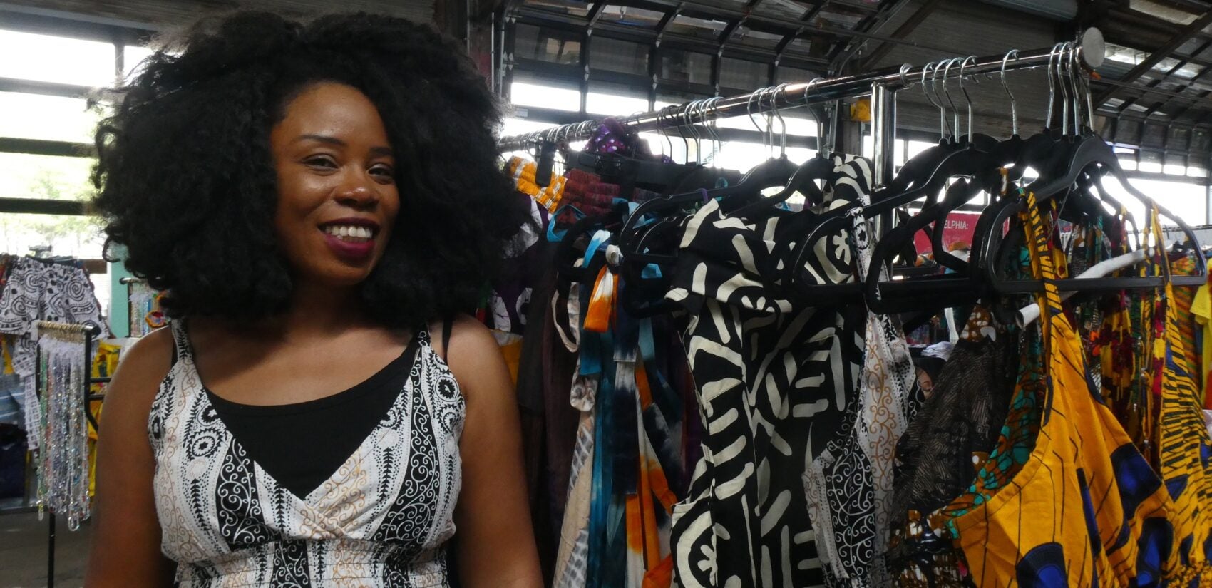 Rose Dousuah smiles next to a rack of clothes