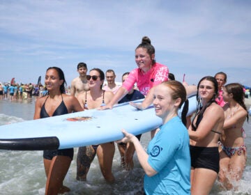 amanda-parezo-NL-080726-01 Amanda Parezo on a surfboard carried by friends