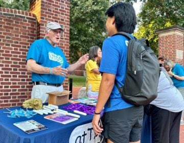 A man speaks with University of Delaware students at a booth