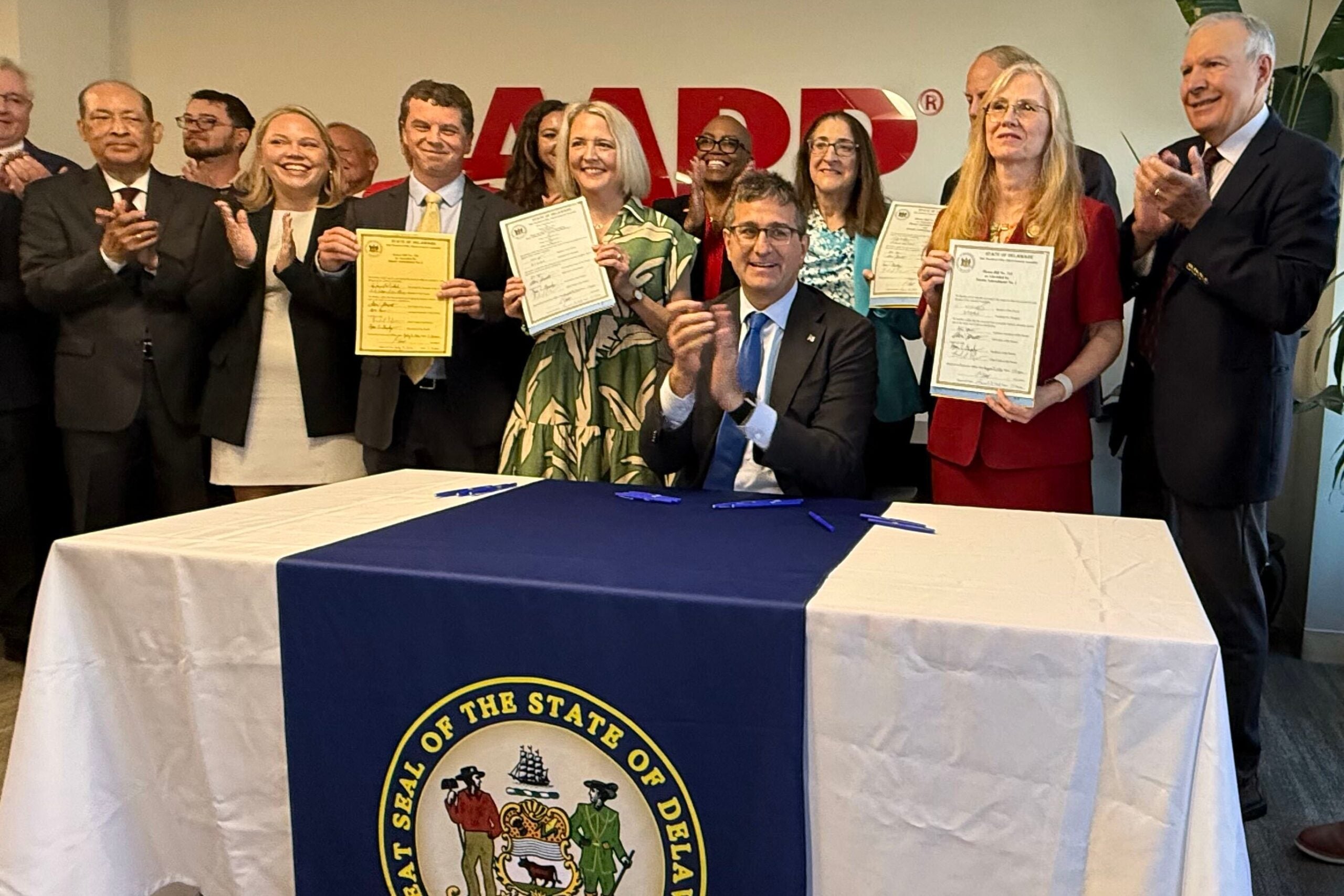 Matt Meyer claps alongside others after signing legislation