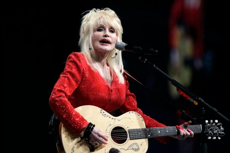 Dolly Parton is singing and playing guitar on stage in Detroit in 2009.