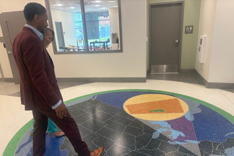 Logan Herring shows Lisa Blunt Rochester a map on a terrazzo tile floor