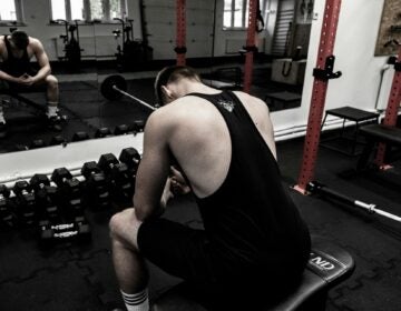 maciej-karon-M4rhdJkvAqQ-unsplash a man sits hunched over in a gym