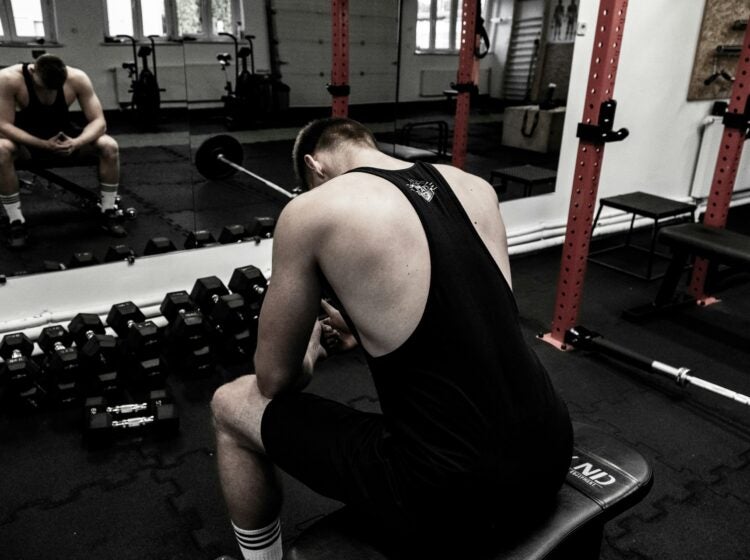 a man sits hunched over in a gym