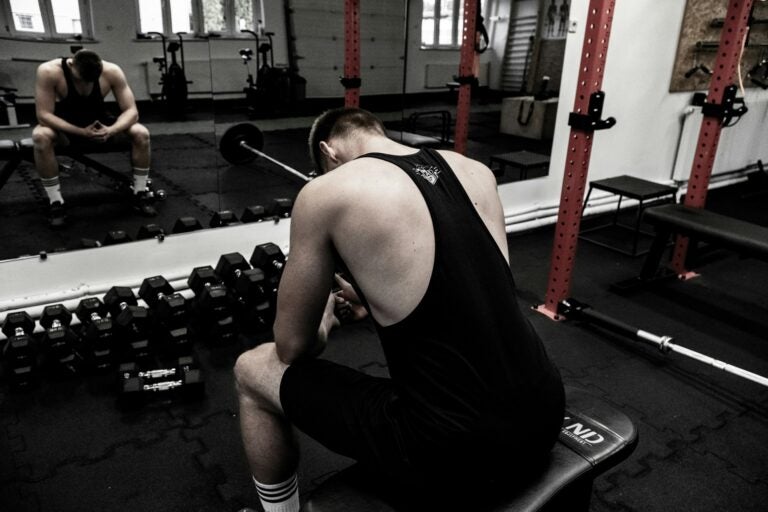 a man sits hunched over in a gym