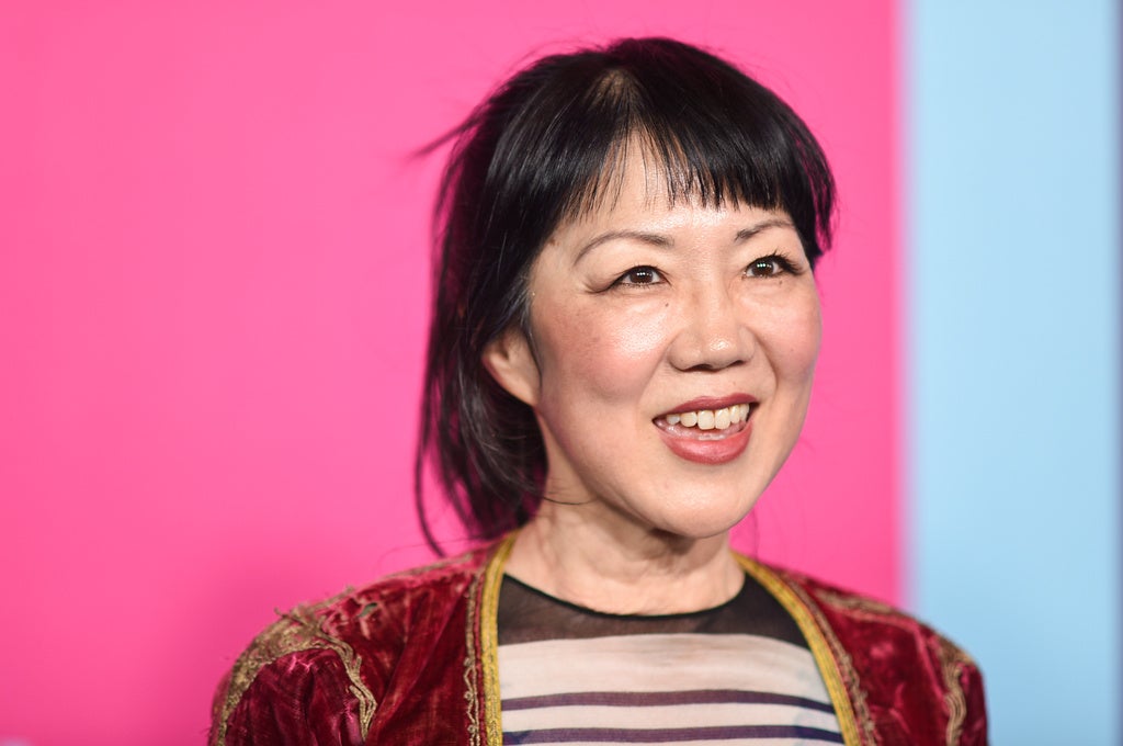 Comedian Margaret Cho smiles against a pink backdrop