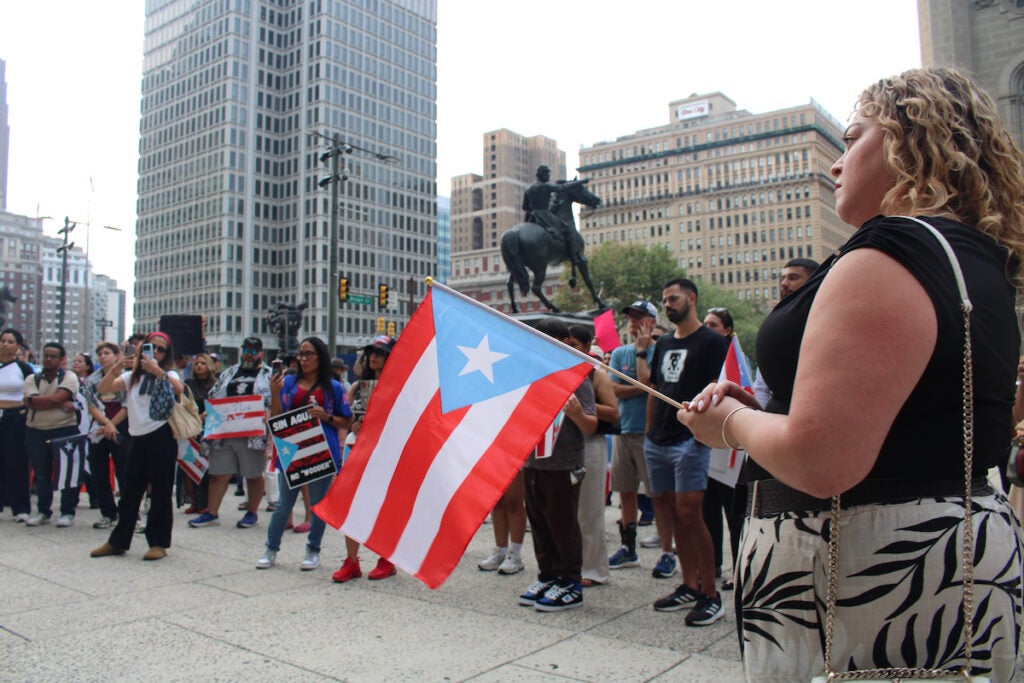 Adamary Sosa, right, one of the rally organizers, holds a Puerto Rican flag