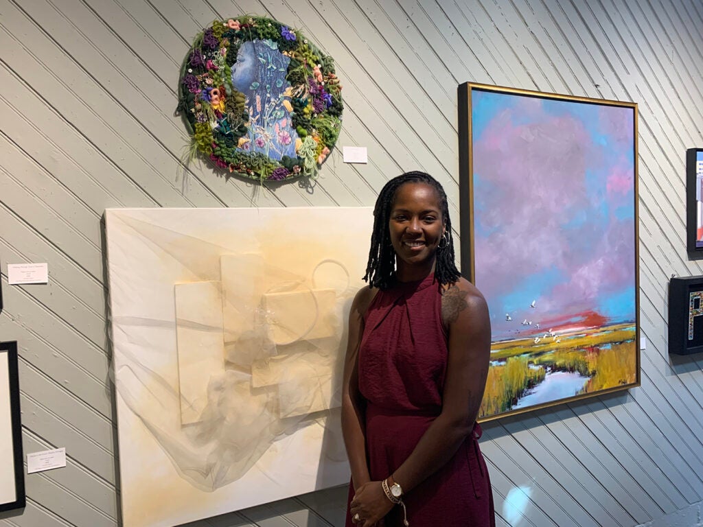 Charlese Phillips stands next to a painting, her own "In The Garden"
