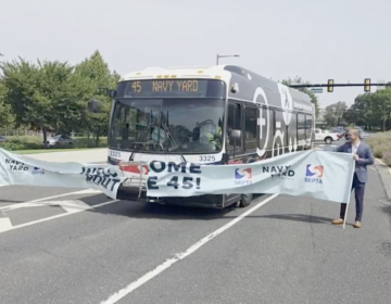 A SEPTA bus breaks through a ceremonial banner as it travels into the Navy Yard for the first time.