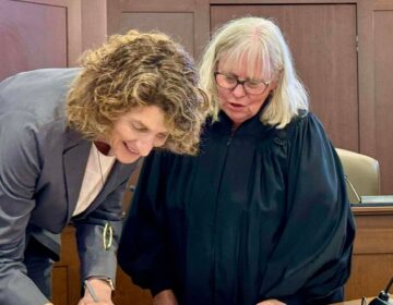 suzanne-goode-delaware Suzanne Goode signing paper next to a judge