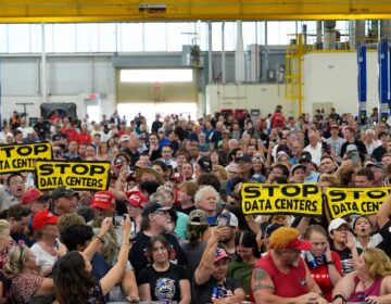 People wait for President Donald Trump to arrive at an event at the General Motors Proving Ground Monday, July 27, 2026, in Milford, Mich. (AP Photo/Paul Sancya)