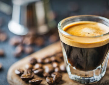 A cup of coffee surrounded by coffee beans