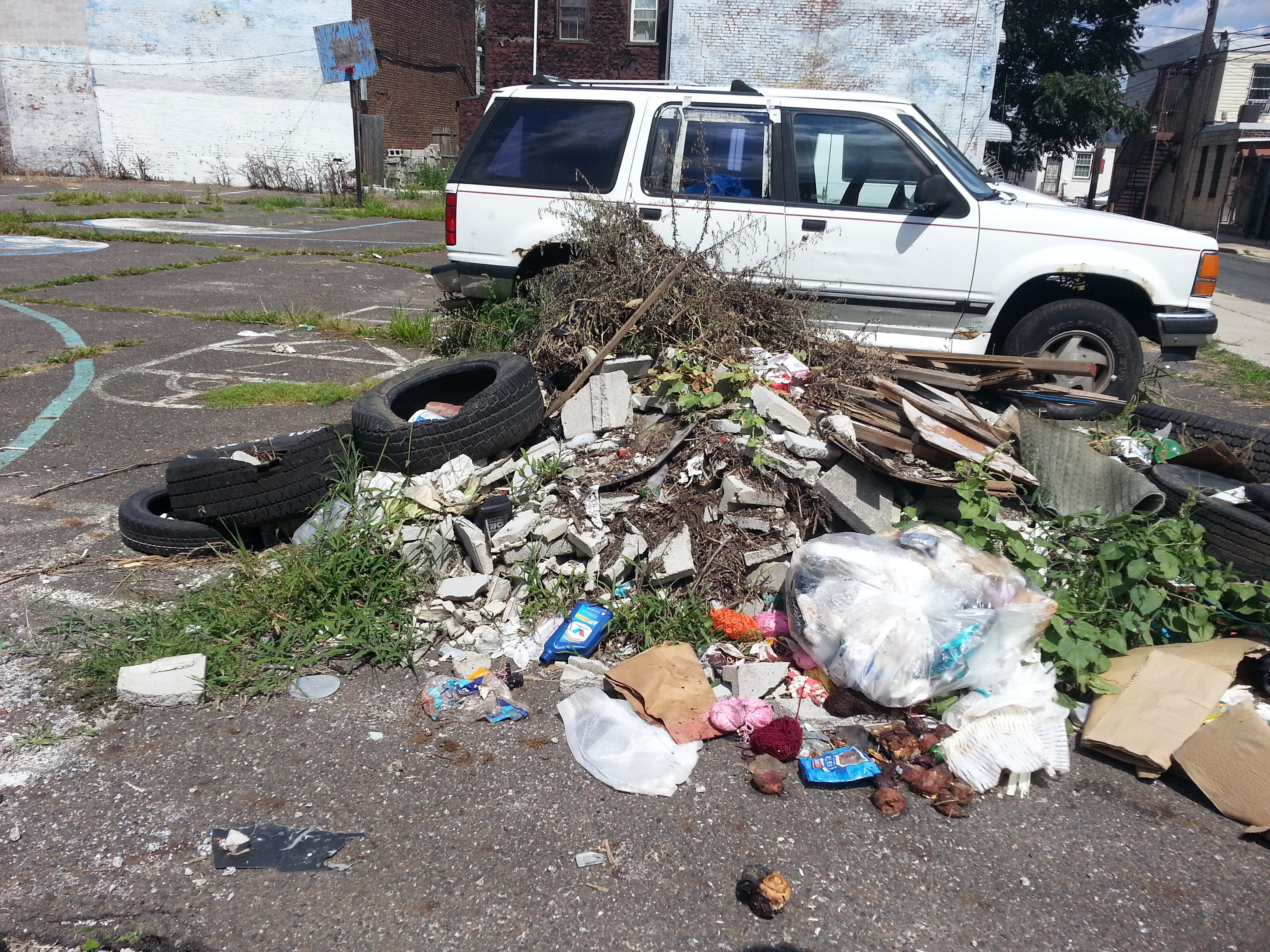 A pile of trash and parked vehicles on the former Helen Street basketball court
