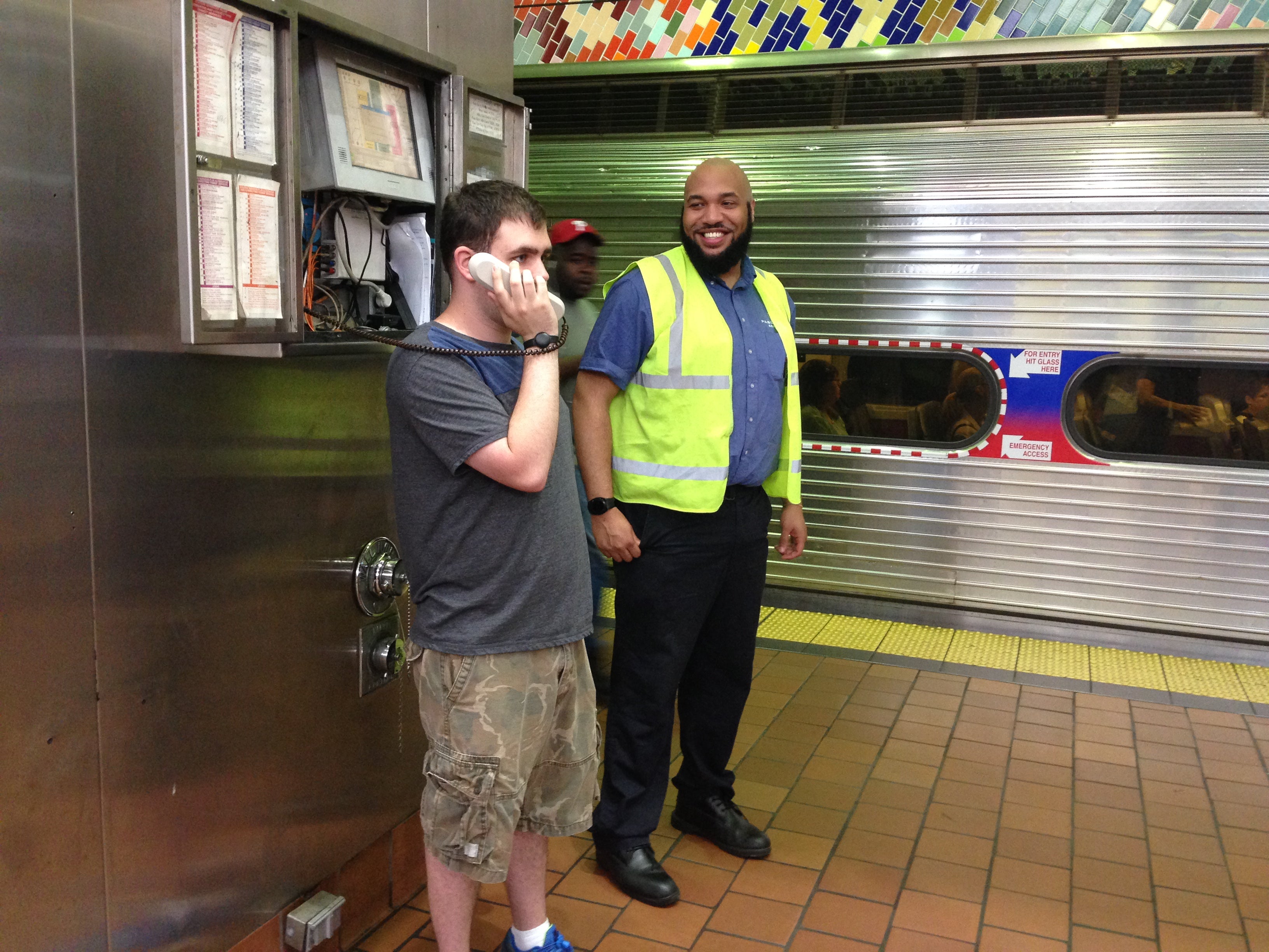 Dirk Green, SEPTA passenger services rep, looks on as Caleb Stone announces an arrival