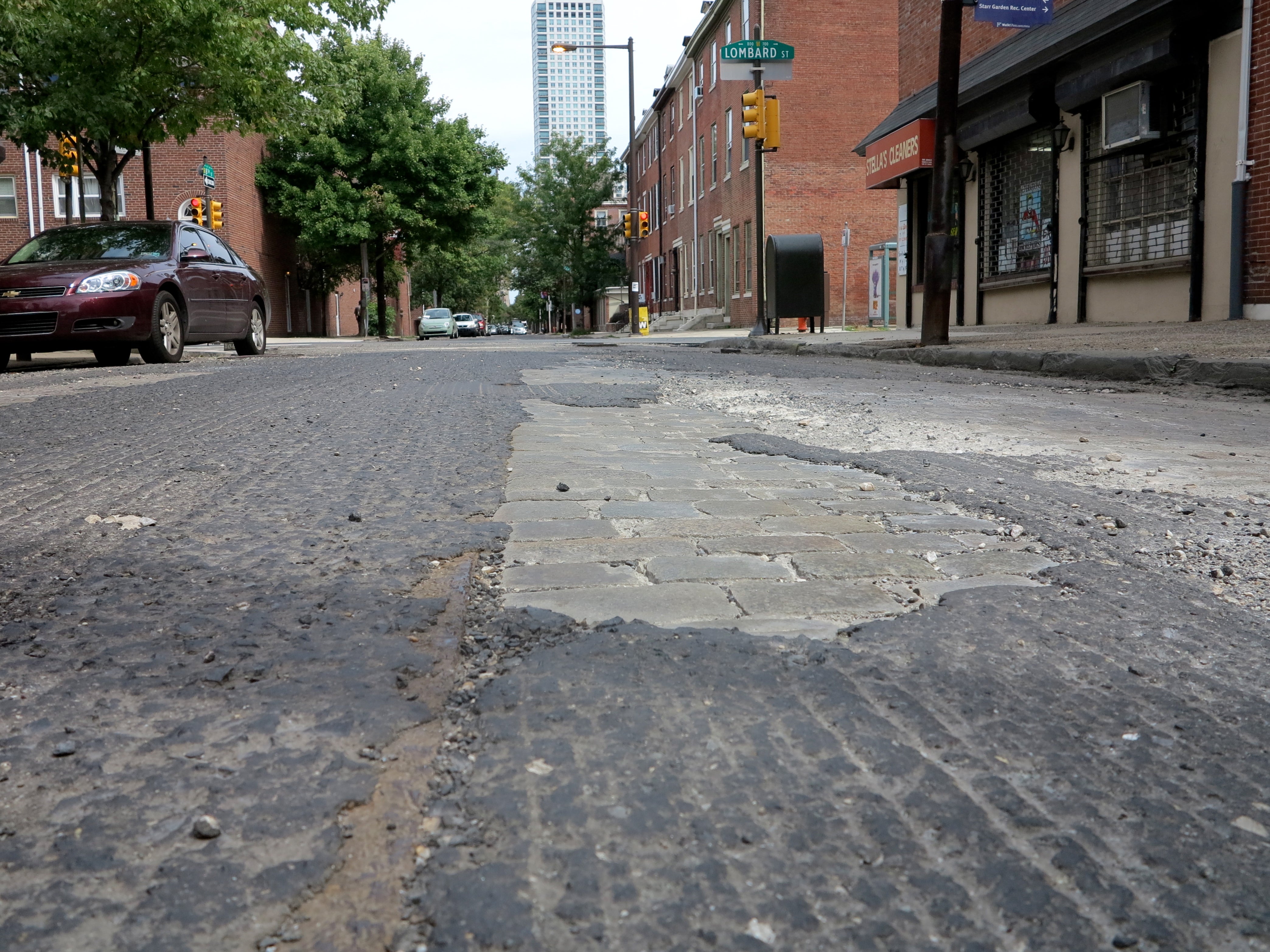Milled road reveals trolley track and cobblestone street buried below the asphalt.
