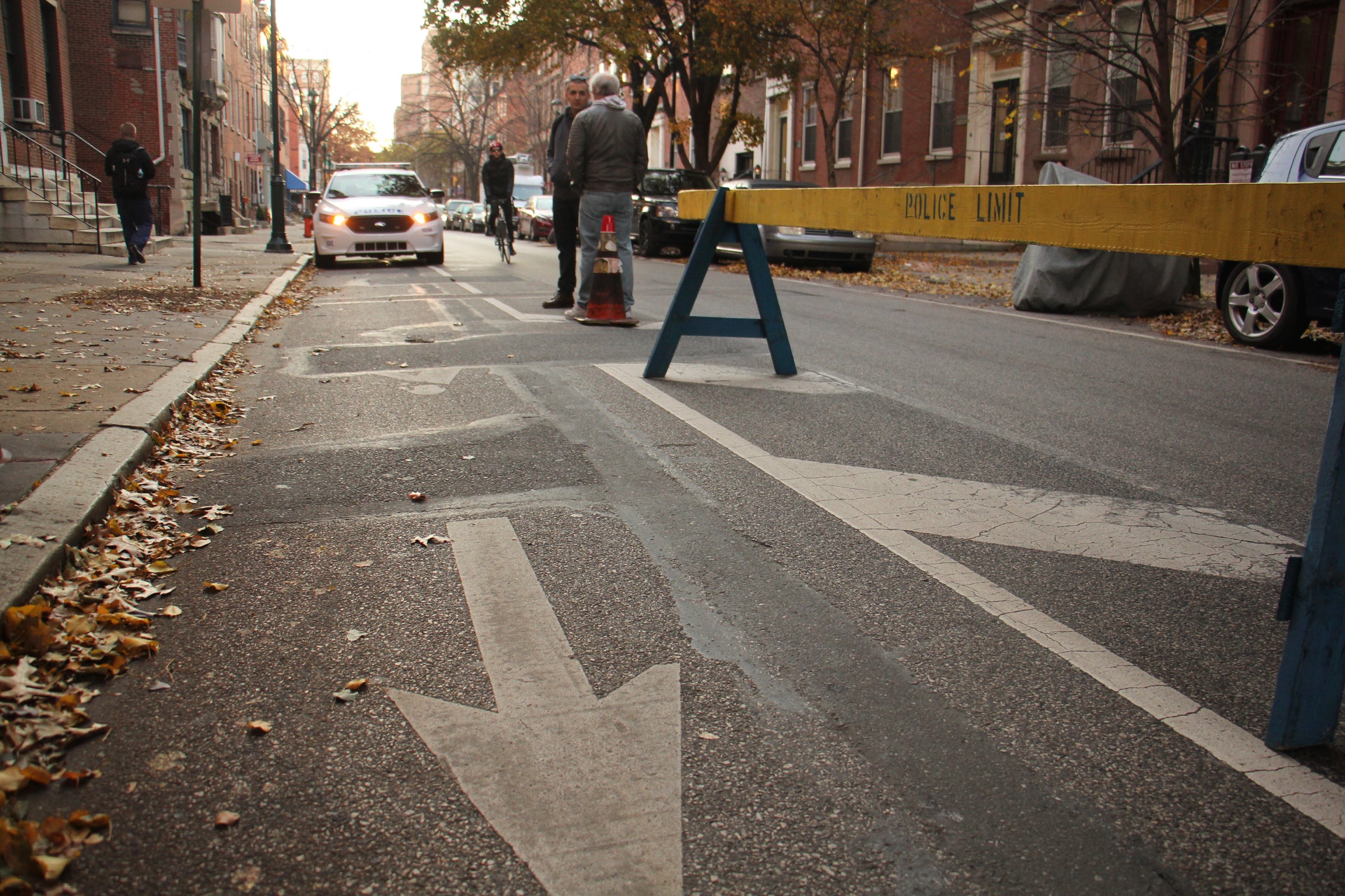 A parked Philadelphia Police car obstructs the bike lane, forcing a cyclist to swerve around into the car lane (Emma Lee, WHYY)